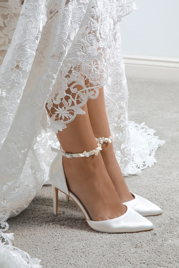 a woman wearing white high heels standing on top of a carpeted floor next to a lace curtain