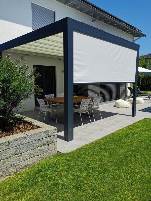 an outdoor covered patio with table and chairs under a white shade over the dining area