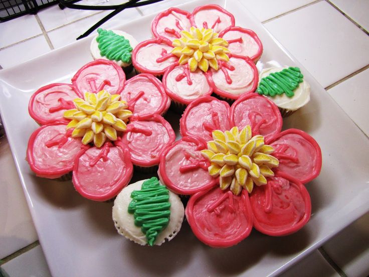 cupcakes decorated with icing and flowers on a plate