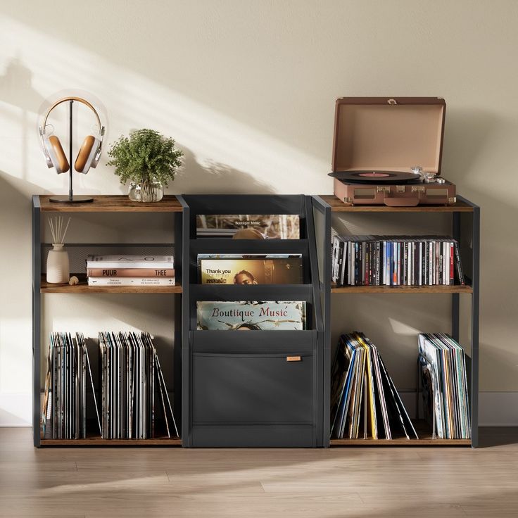 an open book shelf with various records and cds on it, next to a wall mounted record player