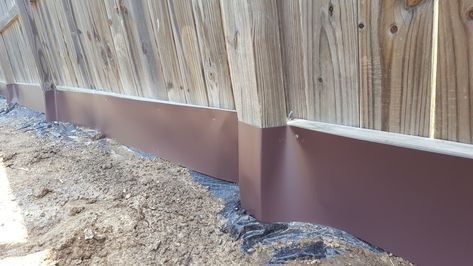 the side of a wooden fence that is being constructed with concrete and wood slats