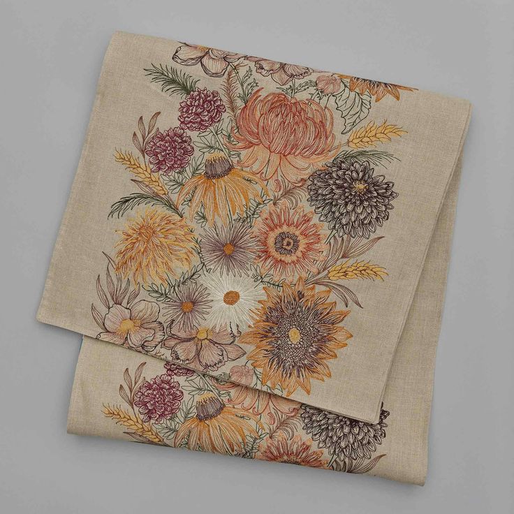 two napkins with flowers on them sitting next to each other in front of a gray background