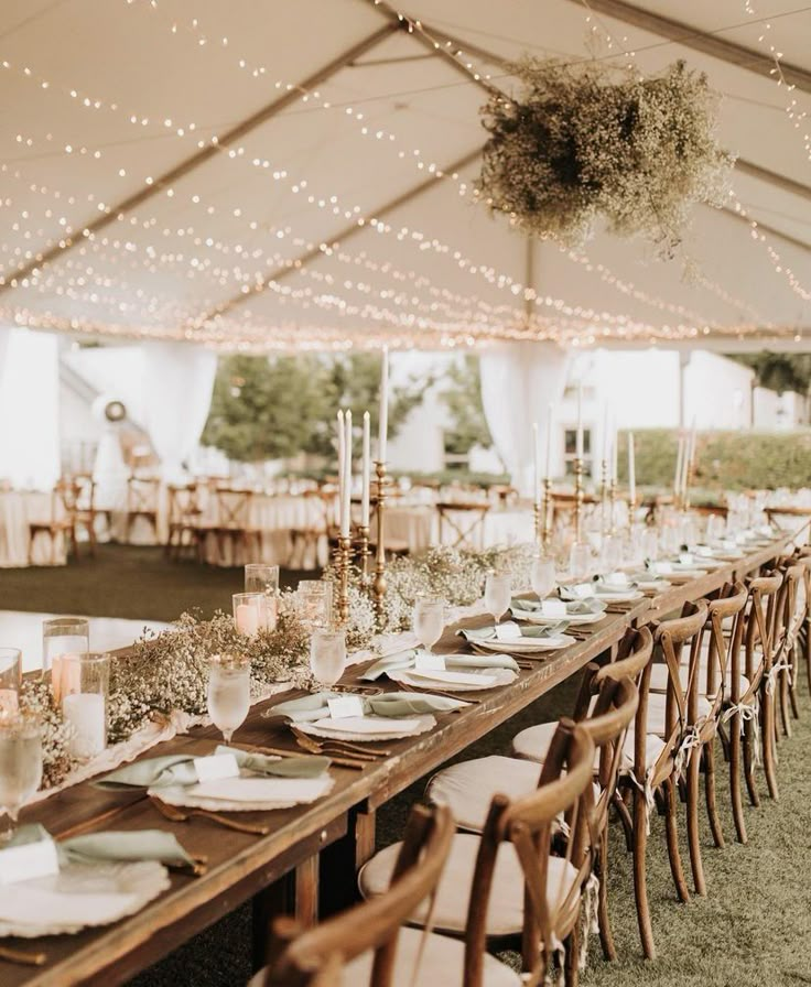 an outdoor tent with tables and chairs set up for dinner