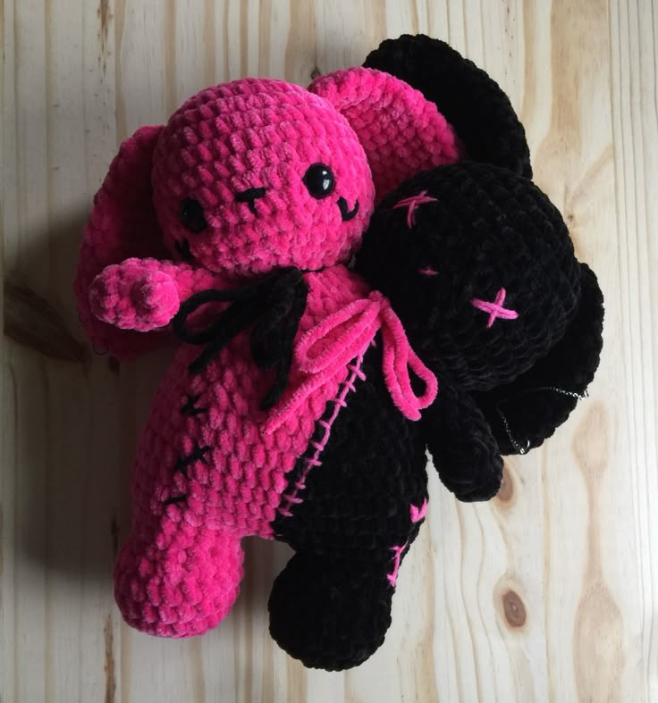 a pink and black stuffed animal laying on top of a wooden floor