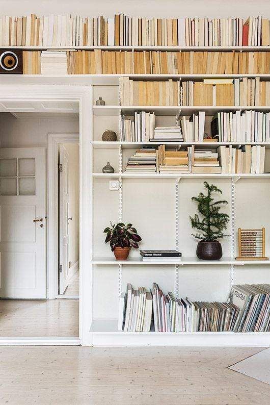 a bookshelf filled with lots of books next to a white door in a living room