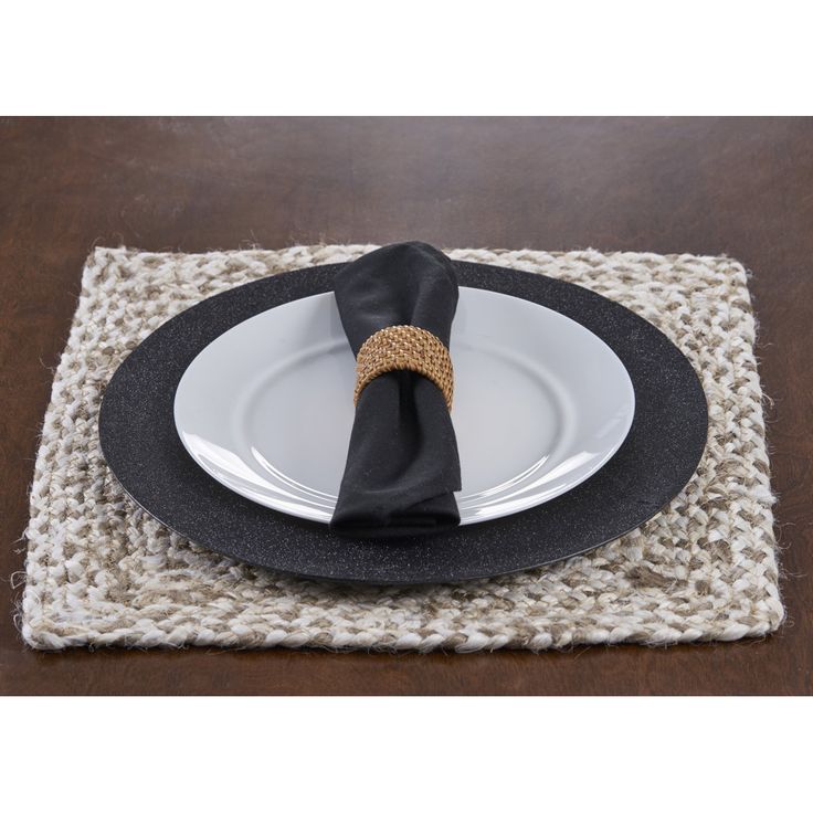 a place mat with a black napkin on top of it and a white plate in the middle