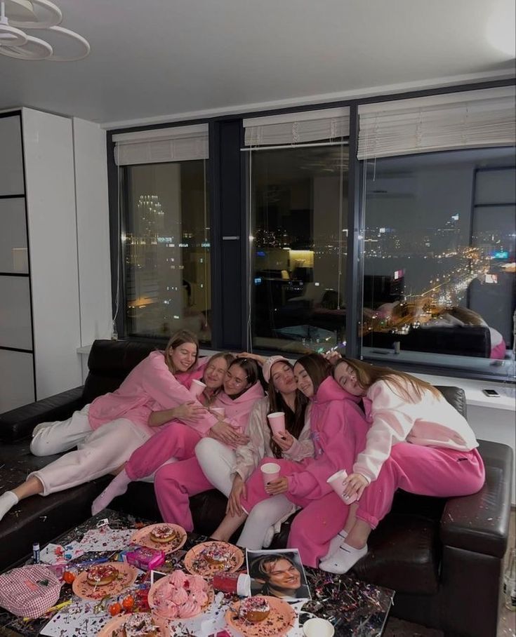 a group of women sitting on top of a couch in front of a table filled with donuts