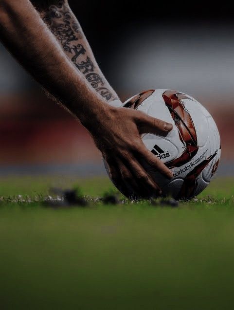 a man holding a soccer ball on top of a field