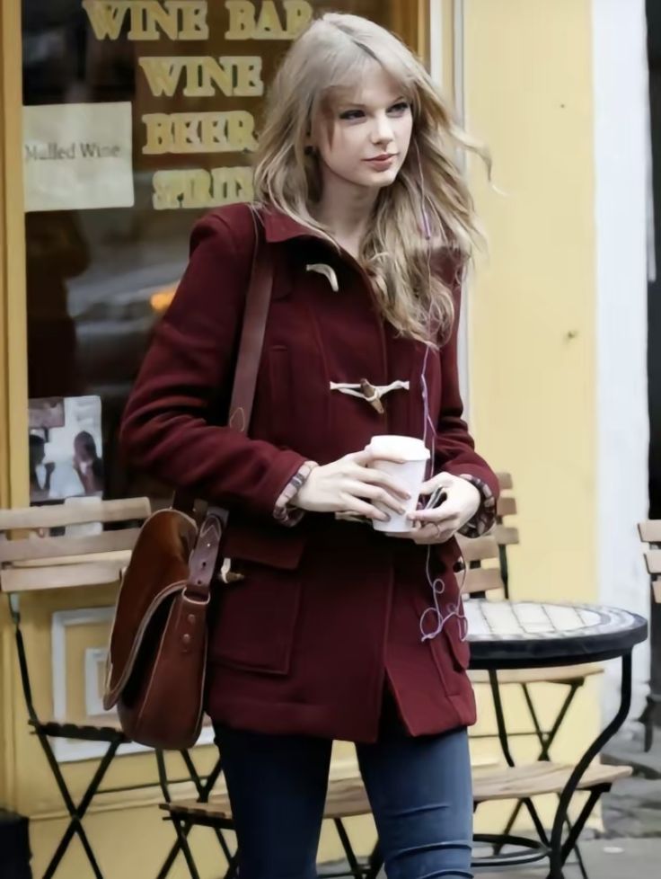 the woman is walking down the street with her coffee