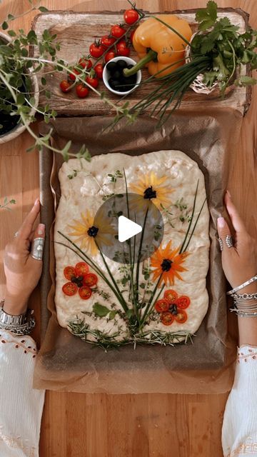 a woman is making a pizza with sunflowers and daisies on the top