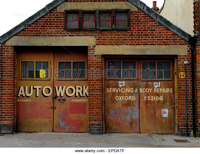 an old brick building with two garage doors and the words auto work painted on it