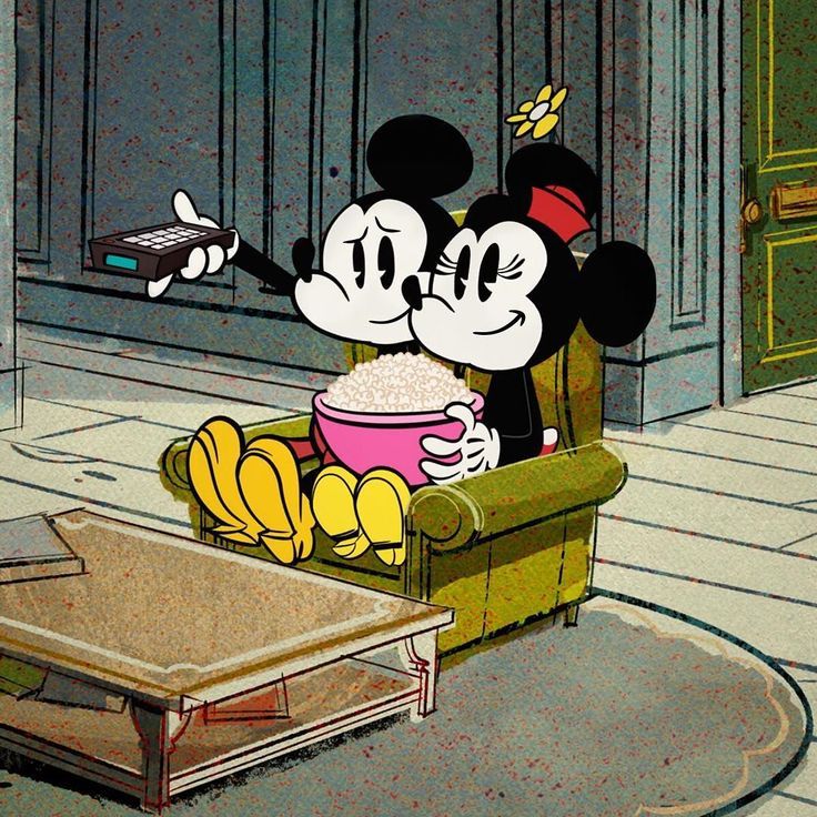 two mickey mouses sitting in a chair eating popcorn