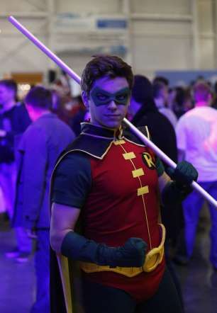 a man dressed as a superhero holding two large swords in front of a crowd at an event