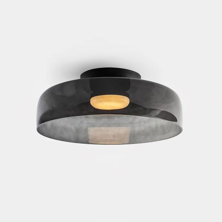 a black and white ceiling light with an orange light in the middle on a gray background