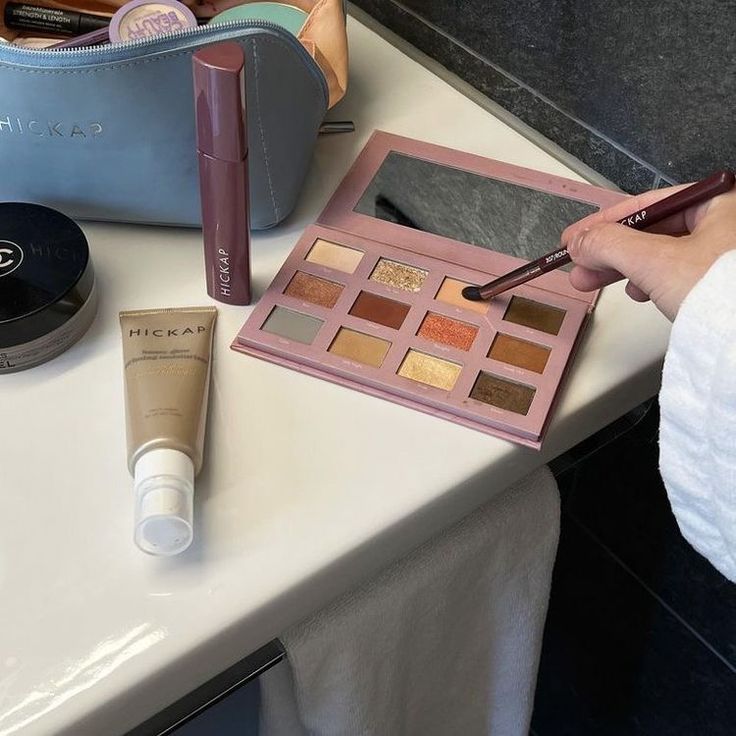 a person is holding a pen and writing on a piece of paper next to some cosmetics