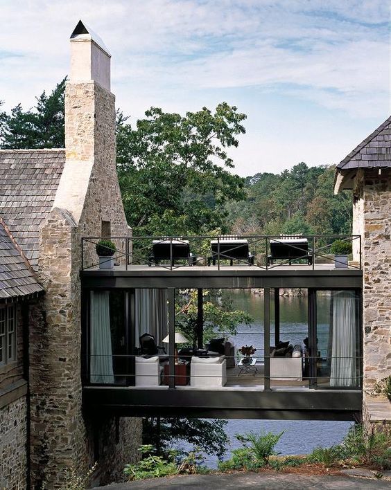 the house is surrounded by water and stone walls, along with an outdoor dining area