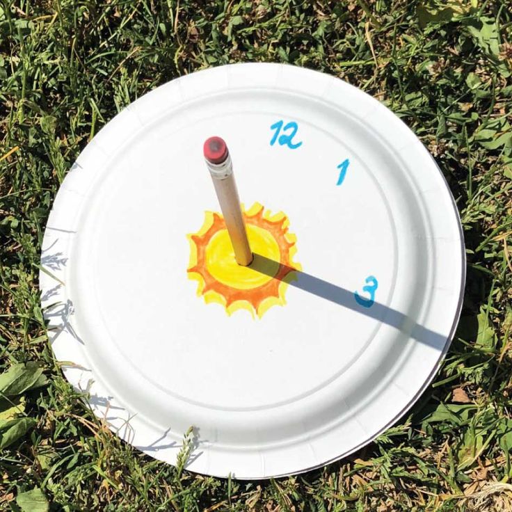 a white frisbee laying on top of grass with a red and yellow clock