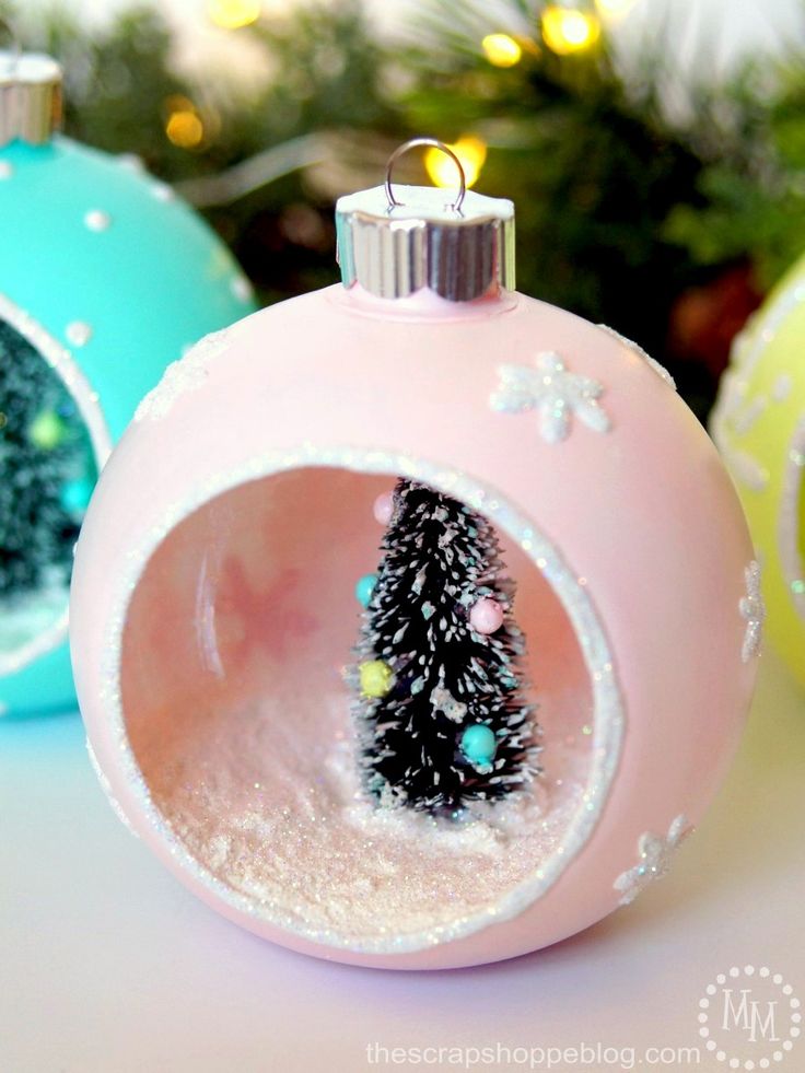 three christmas ornaments sitting on top of a table next to a tree in a glass ornament