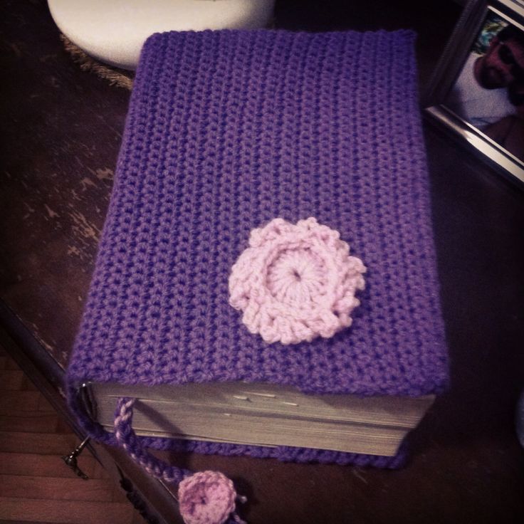 a purple crocheted book with a flower on it