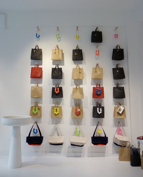 several bags are hanging on the wall in front of a white table and stools