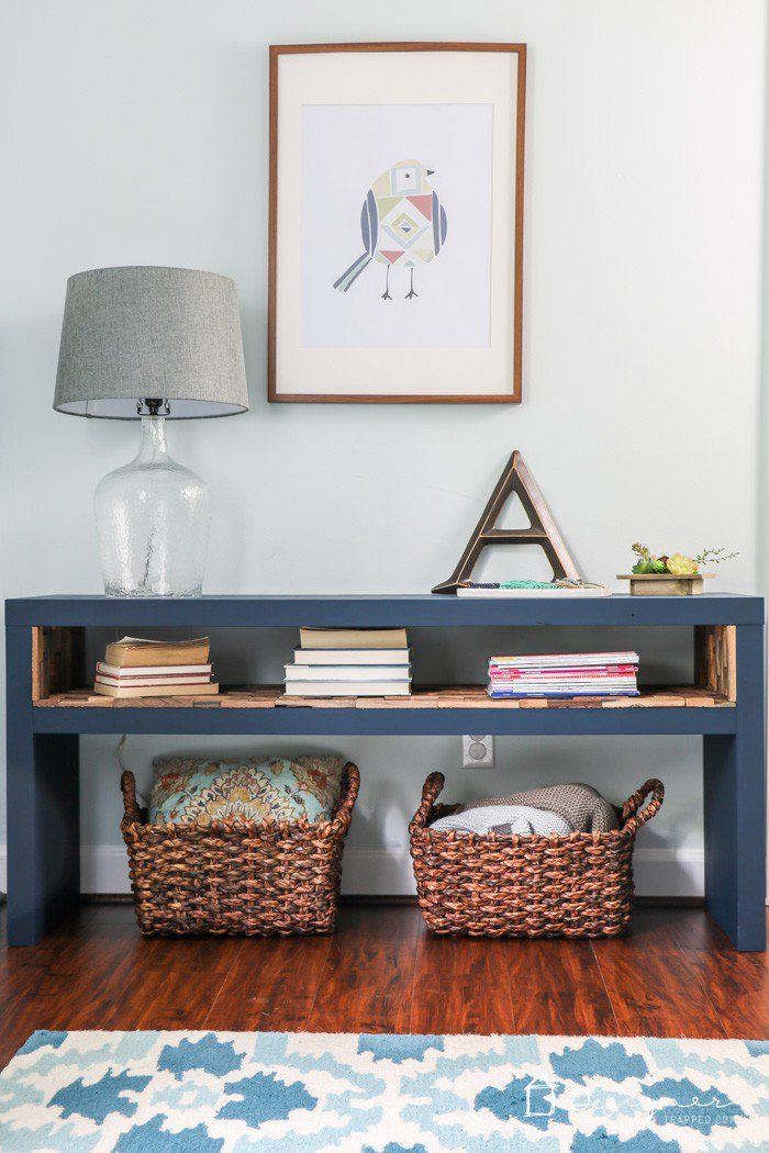 a shelf with two baskets on top of it in front of a painting and lamp