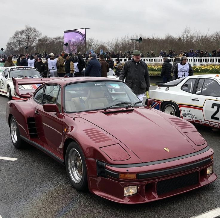 a group of cars parked next to each other in a parking lot with people standing around