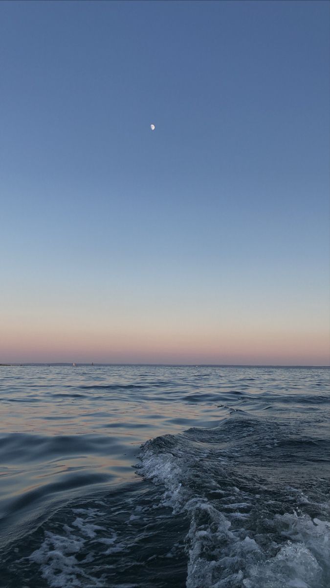 the sun is setting over the ocean as seen from a boat