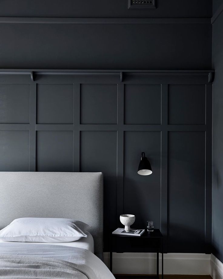 a bed sitting in a bedroom next to a wall with black paneling on it