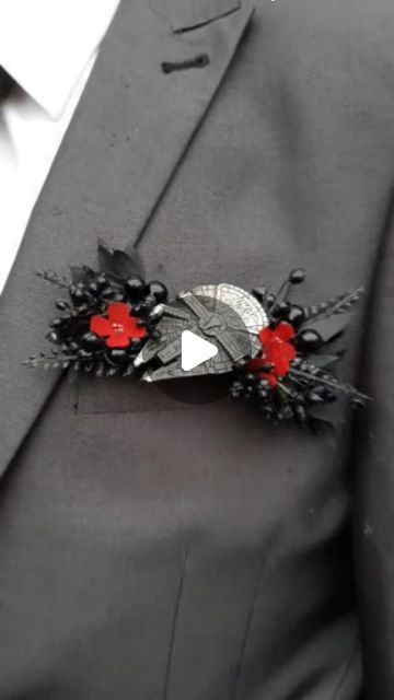 a man wearing a suit and tie with red flowers on the lapel flower pin