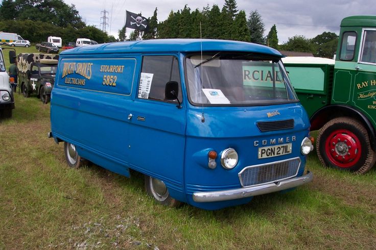 an old blue van is parked next to other green and white trucks in the grass