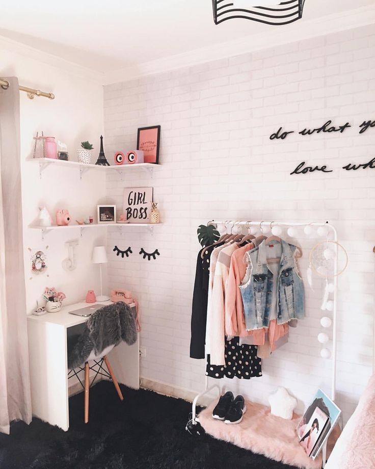 a white room with clothes hanging on the rack and other items sitting on shelves in front of it