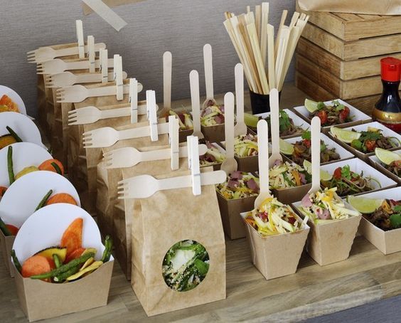 there are many different types of food in the trays on this buffet table with forks and spoons sticking out of them