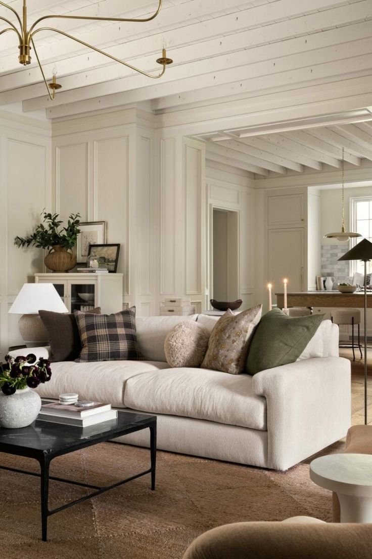 a living room filled with furniture and a chandelier hanging from the ceiling in front of a fireplace