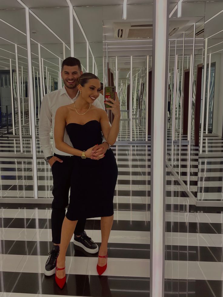 a man and woman taking a selfie in an empty room with black and white tiles