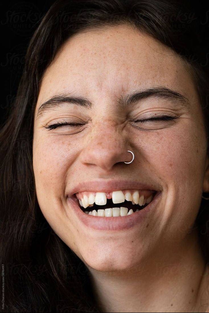 a woman smiling with her eyes closed and nose piercing in the shape of a heart