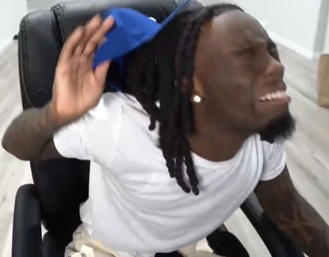 a man with dreadlocks sitting in a chair and holding his hand up to his head