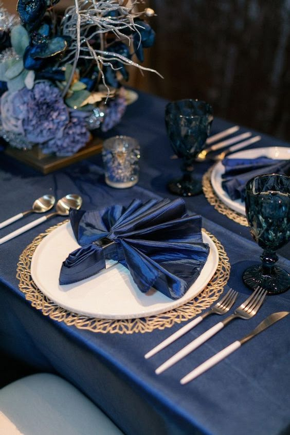 a table set with blue and gold place settings