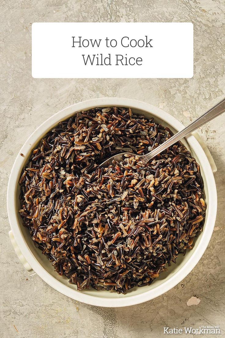 a white bowl filled with wild rice on top of a table next to a spoon