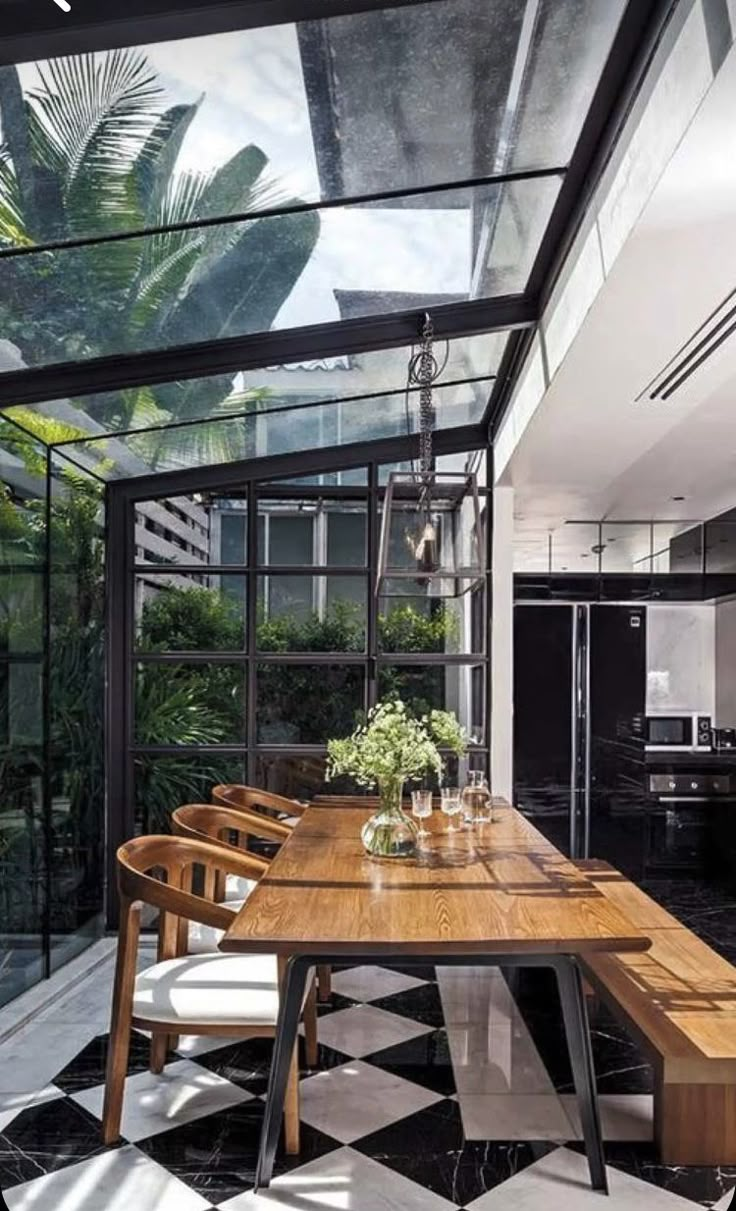 an indoor dining area with black and white checkerboard flooring, glass walls and ceiling