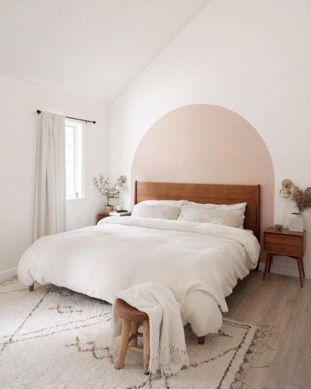 a bedroom with a large bed and white rugs on the floor, in front of a window