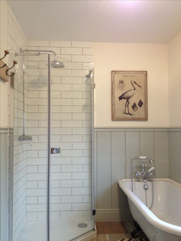 a white bath tub sitting next to a walk in shower under a painting on the wall