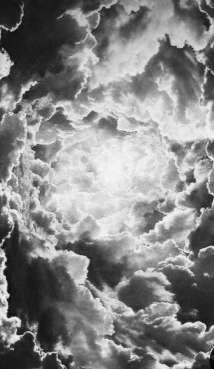 black and white photograph of clouds in the sky with sun shining through it's center