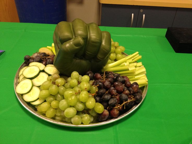 a plate filled with grapes, cucumbers and other fruit on a green table cloth