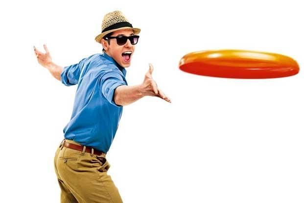 a man in blue shirt and tan pants playing with an orange frisbee on white background