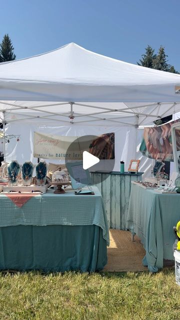 an outdoor market with tables covered in green cloths and white tented awning