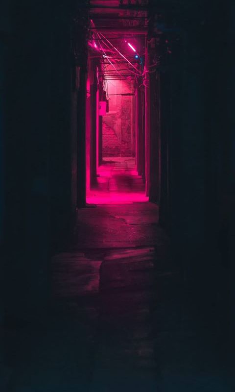 a dark hallway with red light coming from the ceiling