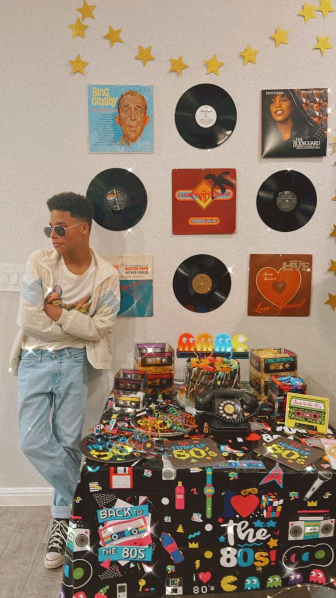 a man standing in front of a table covered with vinyl records and stickers on it