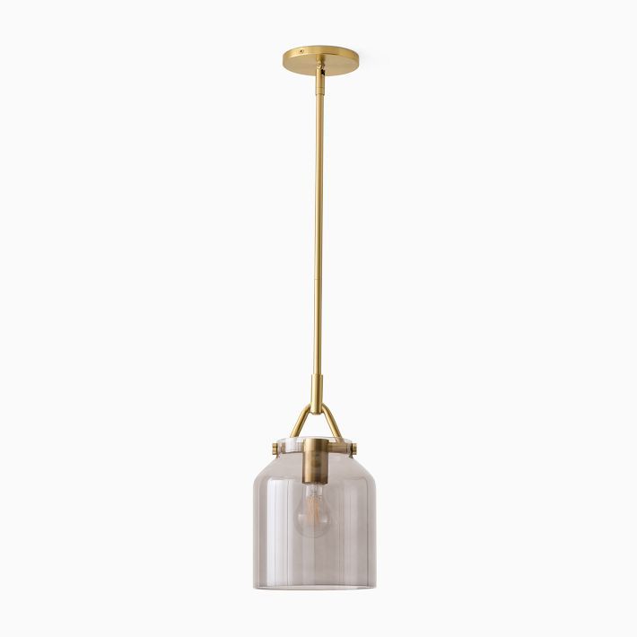 a glass and brass pendant light hanging from the ceiling