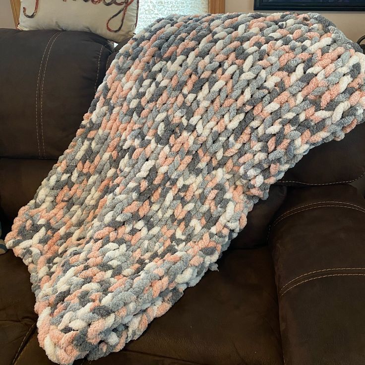 a blanket is sitting on the back of a couch in front of a brown chair