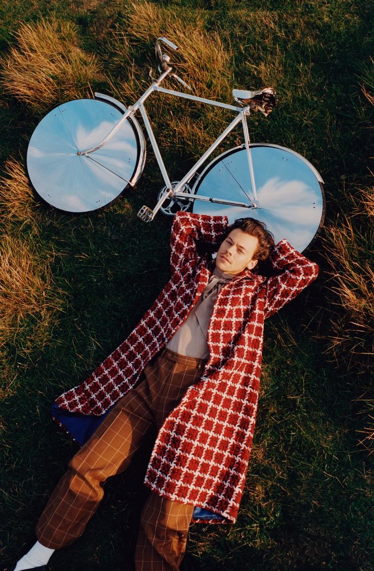 a man laying in the grass next to a bicycle